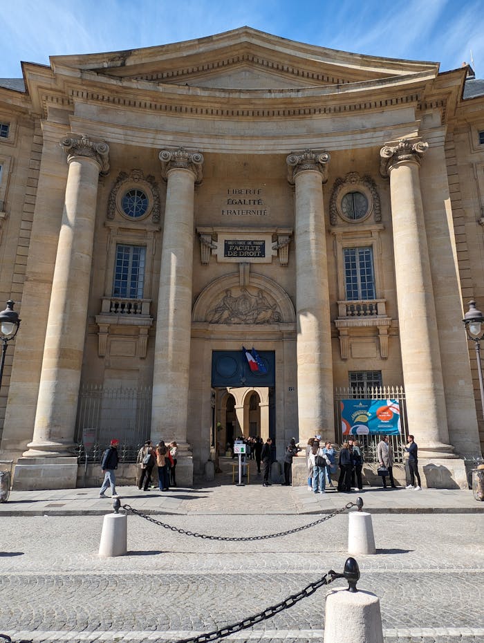 The historical facade of the Sorbonne Faculty of Law in Paris with people gathered outside.
